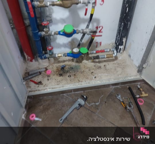 צנרת מים עם ברזים וכלי עבודה על הרצפה